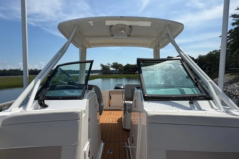 Slide: The Image of 2022 Boston Whaler 240 Vantage boat with open cockpit, docked by a serene lake. - 10