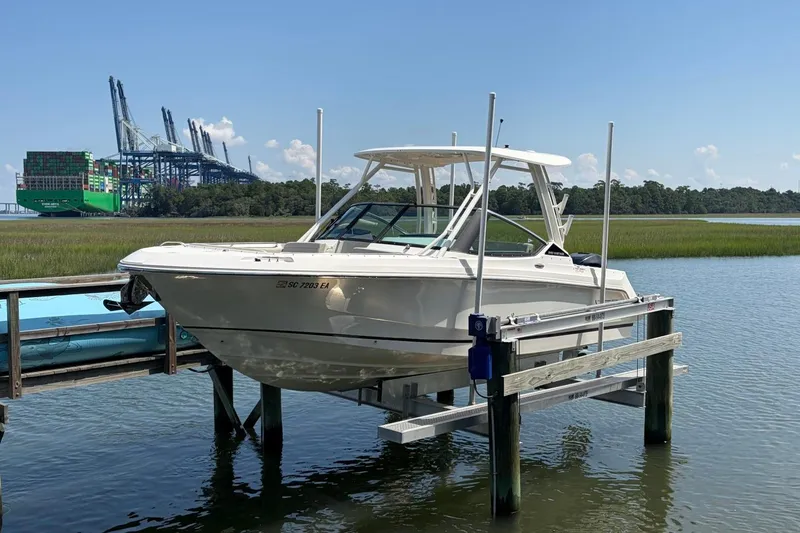 Slide: The Image of 2022 Boston Whaler 240 Vantage boat on lift, with industrial port background. - 2