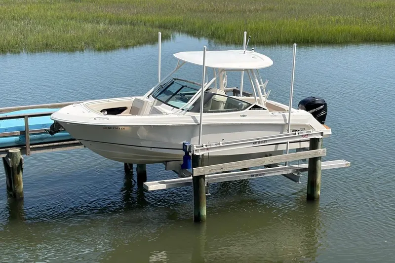 The Image of 2022 Boston Whaler 240 Vantage boat docked on a lift in a serene water setting. - 0