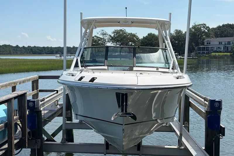 Slide: The Image of 2022 Boston Whaler 240 Vantage boat docked on a lift by a serene lake. - 3
