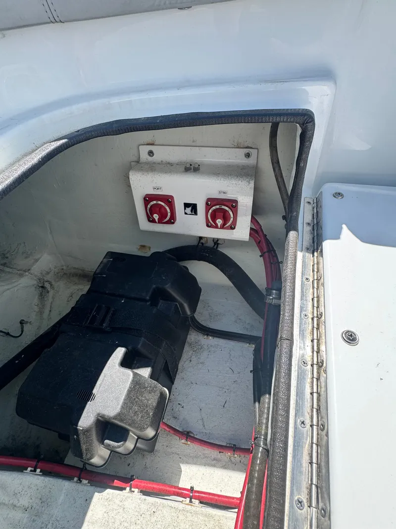 Slide: The Image of A battery compartment with two red switches and wiring in a Contender 24 Sport boat. - 22