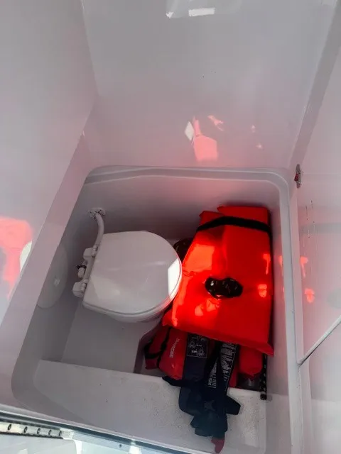 Slide: The Image of A white boat bathroom with a toilet and orange life jackets on the floor. - 18