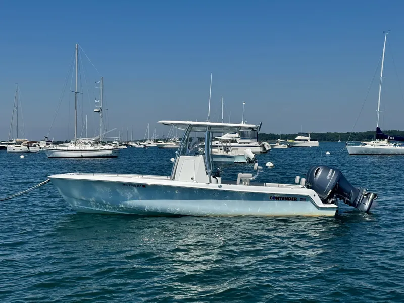 The Image of A 2024 Contender 24 Sport boat on calm water, surrounded by other boats in the harbor. - 0