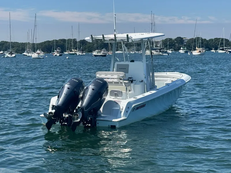 Slide: The Image of A 2024 Contender 24 Sport boat with twin outboard engines on calm water, surrounded by other boats. - 4