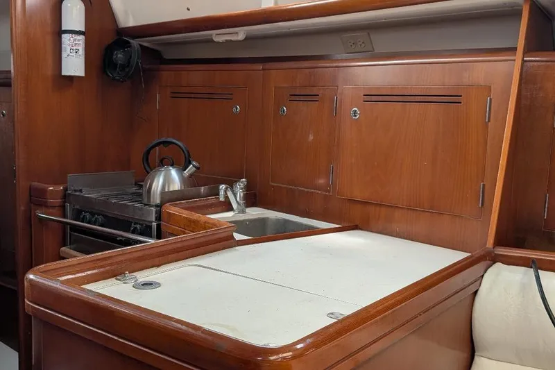 Slide: The Image of Galley kitchen in 2006 Beneteau Oceanis 352 sailboat with wooden cabinetry and stainless steel appliances. - 11