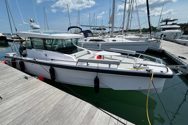 Slide: The Image of 2025 Axopar 29 XC Cross Cabin boat docked at a marina under a clear sky. - 5