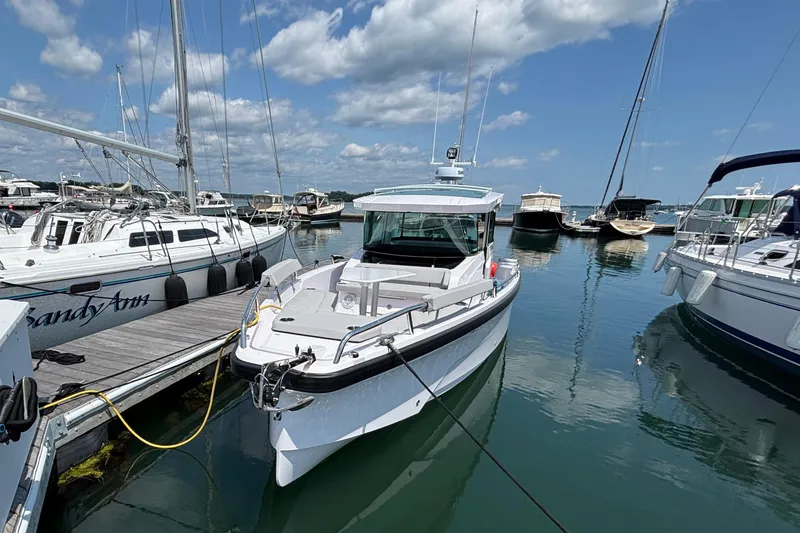 Slide: The Image of 2025 Axopar 29 XC Cross Cabin docked at a marina under a clear blue sky. - 2