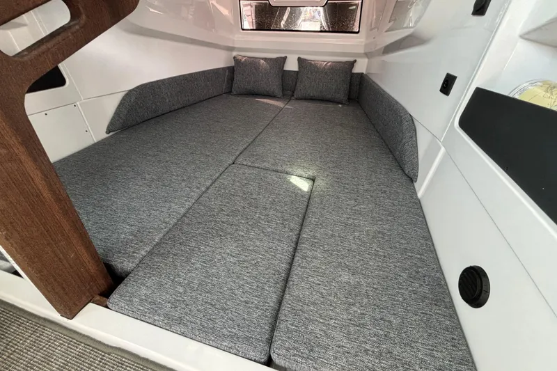 Slide: The Image of 2025 Axopar 29 XC Cross Cabin interior with gray cushioned seating and wooden accents. - 21