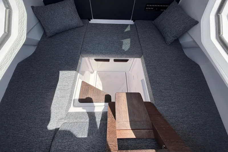 Slide: The Image of 2025 Axopar 29 XC Cross Cabin interior with gray cushions and wooden accents. - 23