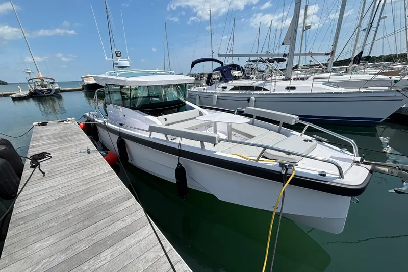 Slide: The Image of 2025 Axopar 29 XC Cross Cabin docked at a marina, surrounded by sailboats. - 1