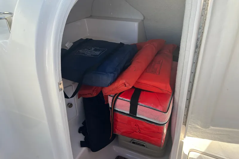 Slide: The Image of Storage compartment in a 2009 Regal 2400 Bowrider with life jackets and safety gear. - 33