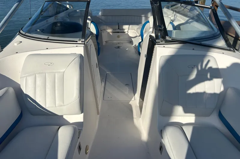 Slide: The Image of 2009 Regal 2400 Bowrider interior with white seating and blue accents, docked by water. - 49