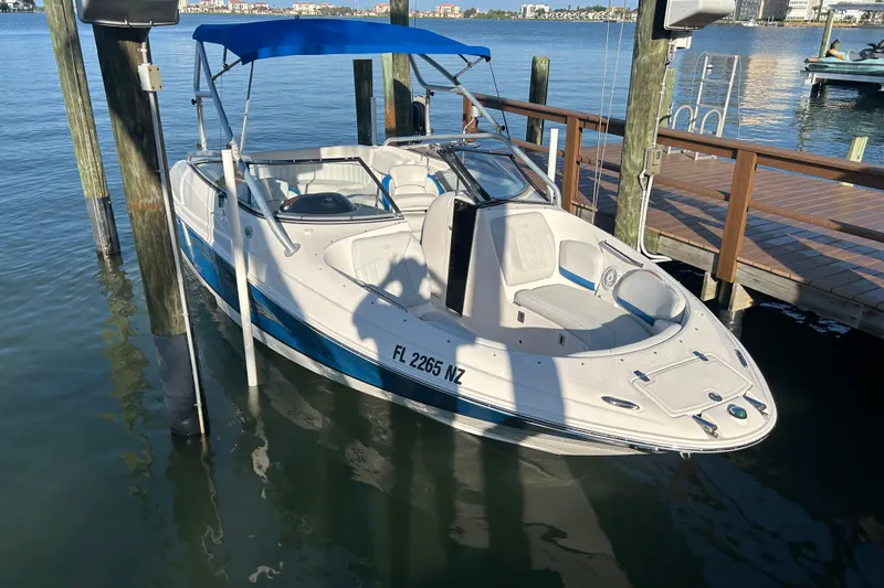 Slide: The Image of 2009 Regal 2400 Bowrider boat docked with blue canopy, calm water background. - 9