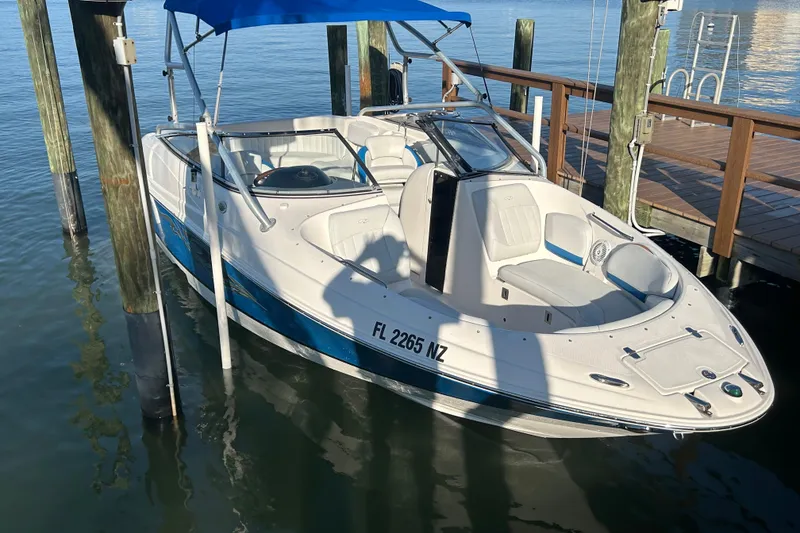 Slide: The Image of 2009 Regal 2400 Bowrider boat docked with blue canopy, white and blue design. - 10