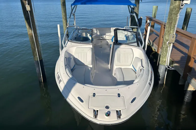 Slide: The Image of 2009 Regal 2400 Bowrider boat docked, featuring spacious seating and blue canopy. - 8