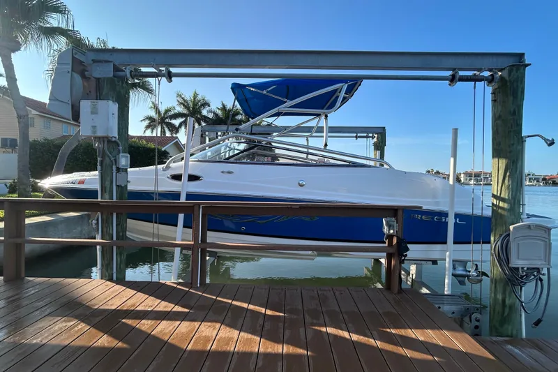 Slide: The Image of 2009 Regal 2400 Bowrider boat on lift, dockside with palm trees in background. - 6