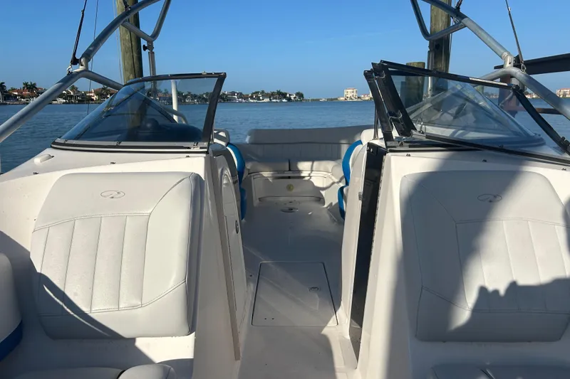 Slide: The Image of 2009 Regal 2400 Bowrider boat interior with open seating, docked by calm waters. - 50