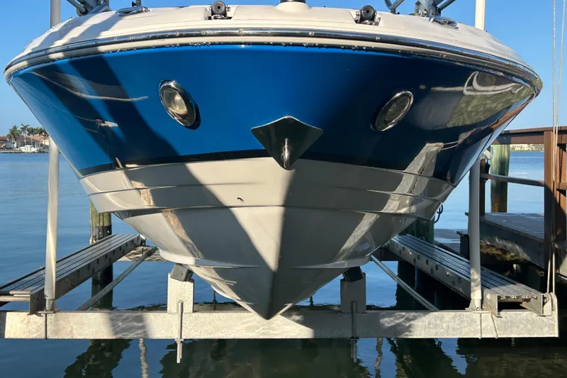 Slide: The Image of 2009 Regal 2400 Bowrider boat on lift, blue hull, dockside view. - 2