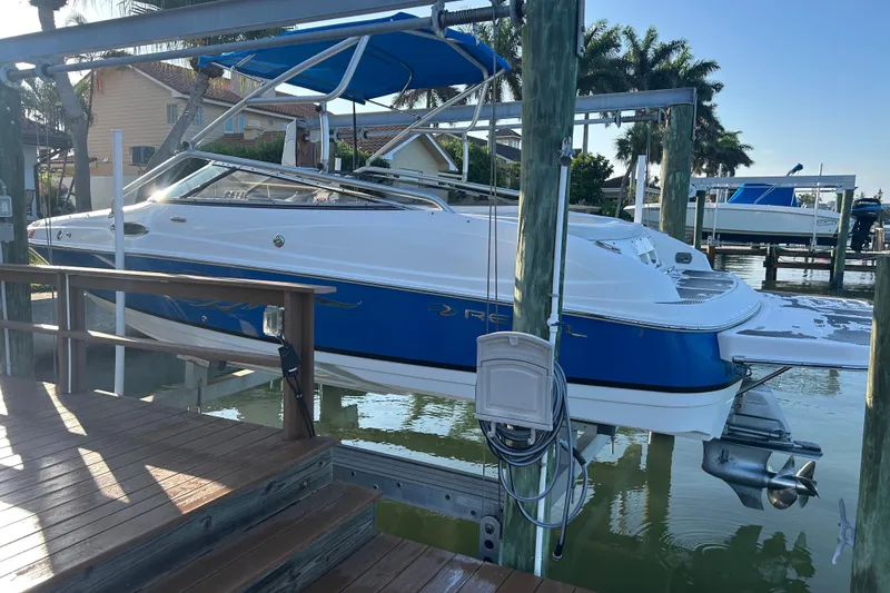 Slide: The Image of 2009 Regal 2400 Bowrider boat docked, featuring blue and white design with canopy. - 5
