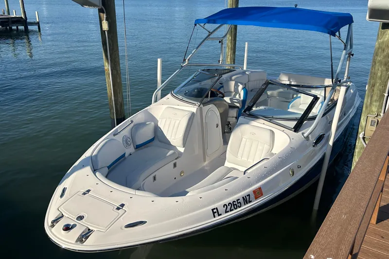Slide: The Image of 2009 Regal 2400 Bowrider boat docked with blue canopy, white seating, and sleek design. - 11