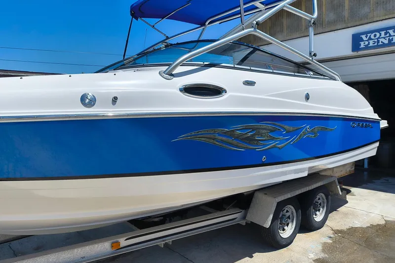 Slide: The Image of 2009 Regal 2400 Bowrider boat with blue and white design on a trailer. - 0