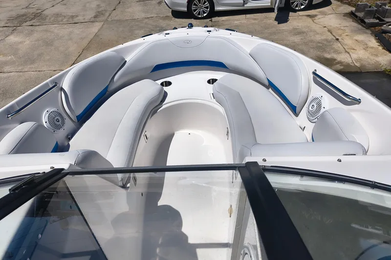 Slide: The Image of 2009 Regal 2400 Bowrider boat interior with white and blue seating, parked on concrete. - 3