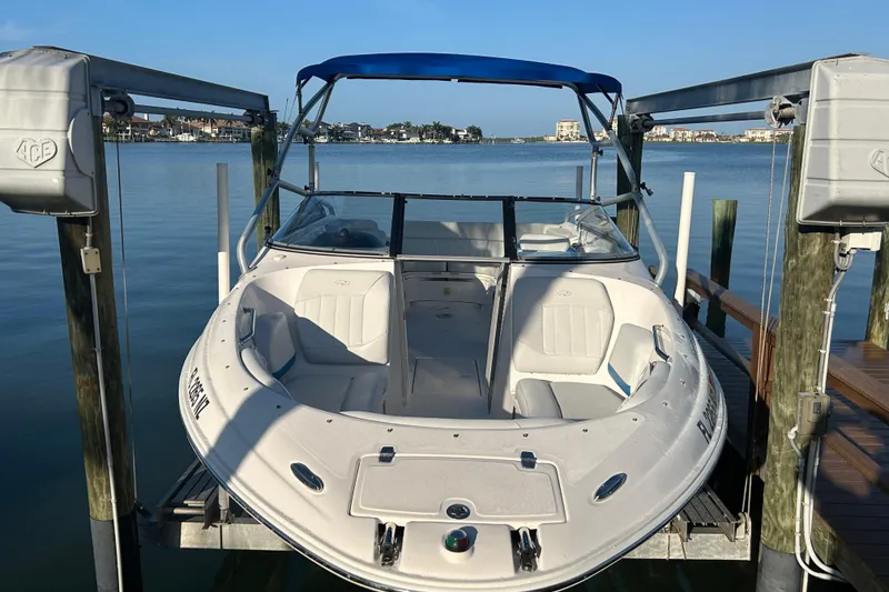 Slide: The Image of 2009 Regal 2400 Bowrider boat docked on a lift, with a scenic waterfront view. - 3