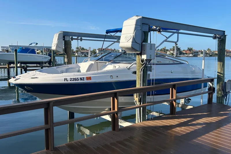 Slide: The Image of 2009 Regal 2400 Bowrider boat docked on a lift by the waterfront. - 7