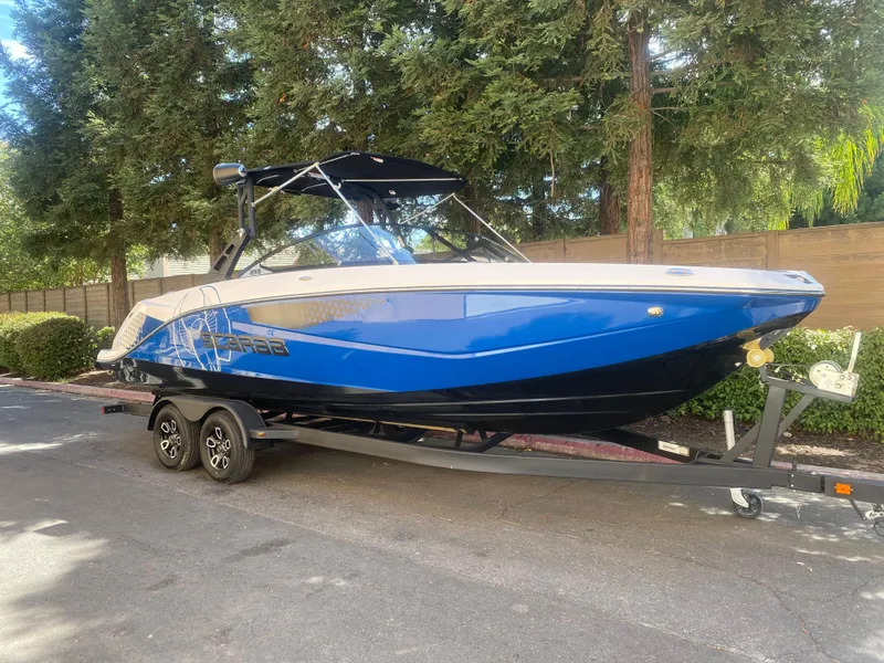 The Image of 2025 Scarab 255 ID boat on trailer, blue and white, parked outdoors. - 0