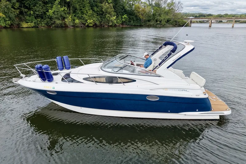 Slide: The Image of 2009 Regal 3060 Window Express boat cruising on a calm lake with lush green shoreline. - 10