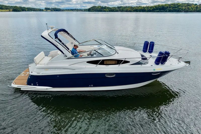 Slide: The Image of 2009 Regal 3060 Window Express boat cruising on a serene lake under a cloudy sky. - 11