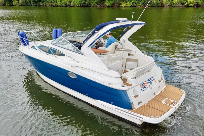 Slide: The Image of 2009 Regal 3060 Window Express boat cruising on a serene lake with lush green surroundings. - 7