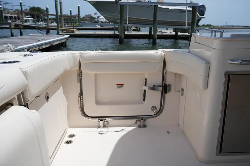 Slide: The Image of 2018 Grady-White Freedom 325 boat interior, featuring a sleek, white seating area by the dock. - 19