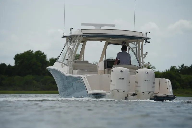 Slide: The Image of 2018 Grady-White Freedom 325 boat cruising on water with twin Yamaha engines. - 16