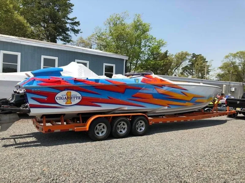 Slide: The Image of 2003 Cigarette 38' Top Gun with a striking, colorful design on a trailer. - 3