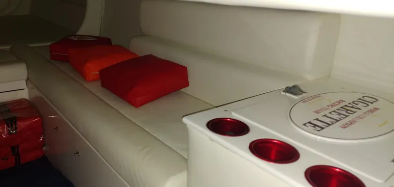 Slide: The Image of The image shows the interior of a 2003 Cigarette 38' Top Gun boat with white seating and red cushions. - 18