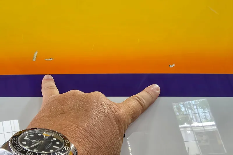 Slide: The Image of Hand pointing at paint chips on 2003 Cigarette 38' Top Gun boat with colorful design. - 30