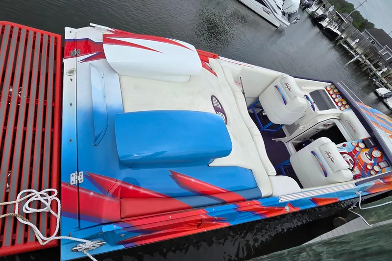 Slide: The Image of 2003 Cigarette 38' Top Gun speedboat with vibrant red, blue, and white design docked at marina. - 2