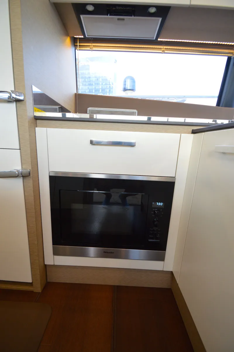 Slide: The Image of The 2017 Prestige 630 kitchen features a built-in Miele oven beneath a window. - 18