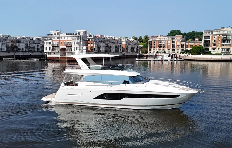 Slide: The Image of A sleek white yacht cruising in a calm harbor with modern buildings in the background. - 6