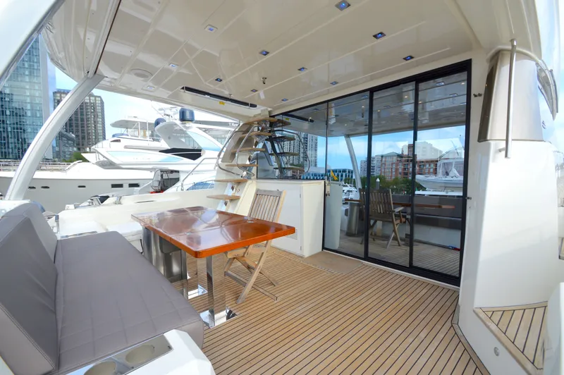 Slide: The Image of The 2017 Prestige 630 features an elegant outdoor deck with a wooden table and cushioned seating. - 8