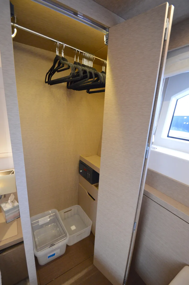 Slide: The Image of An open closet with hangers, two bins, and a safe. A window is visible. - 49