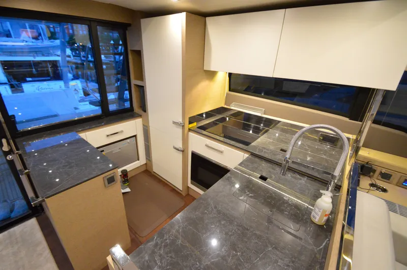 Slide: The Image of The kitchen of a 2017 Prestige 630 yacht with modern appliances and marble countertops. - 22