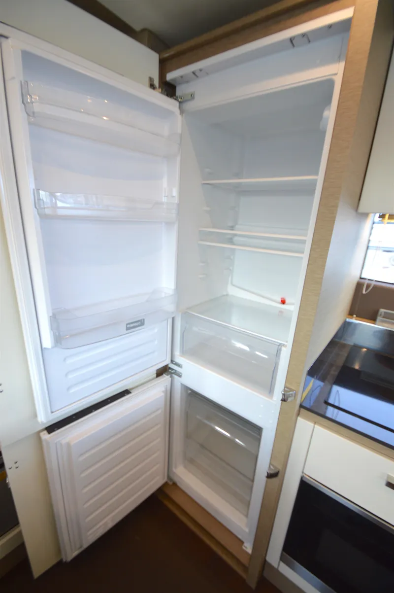 Slide: The Image of An open refrigerator with multiple shelves and drawers in a modern kitchen. - 21