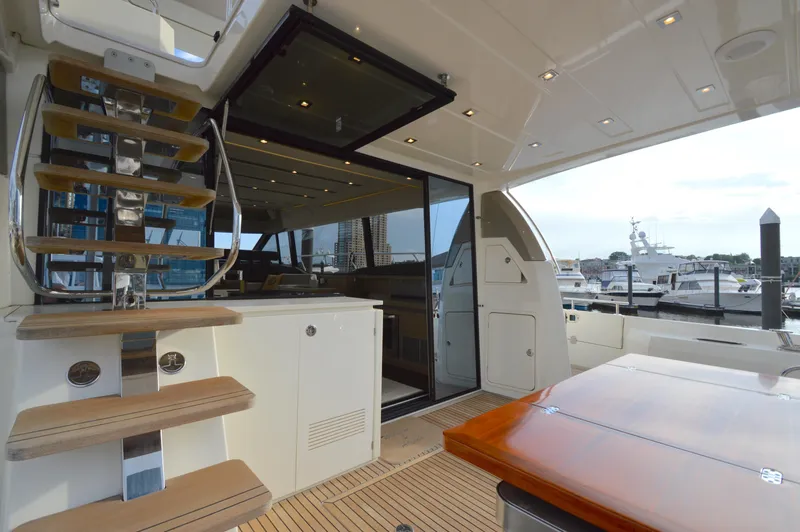 Slide: The Image of The 2017 Prestige 630 features an elegant outdoor deck with a wooden table and stairs to the flybridge. - 10