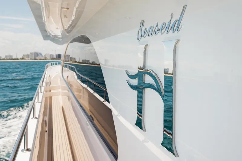 Slide: The Image of 2016 Hargrave Flybridge Motor Yacht cruising near a coastal city, featuring sleek design and branding. - 48