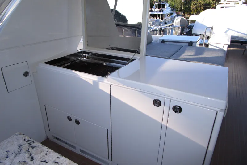 Slide: The Image of Outdoor kitchen area on a 2016 Hargrave Flybridge Motor Yacht, featuring a grill and storage cabinets. - 57