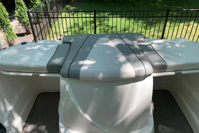 Slide: The Image of 2011 Bayliner 185 Bowrider boat interior with cushioned seating and fenced garden view. - 14