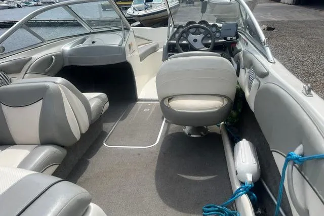 Slide: The Image of 2011 Bayliner 185 Bowrider interior with gray seating and steering wheel, docked by water. - 7
