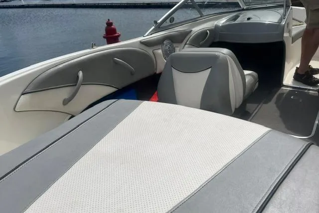 Slide: The Image of 2011 Bayliner 185 Bowrider interior with gray and white seating, docked by water. - 6